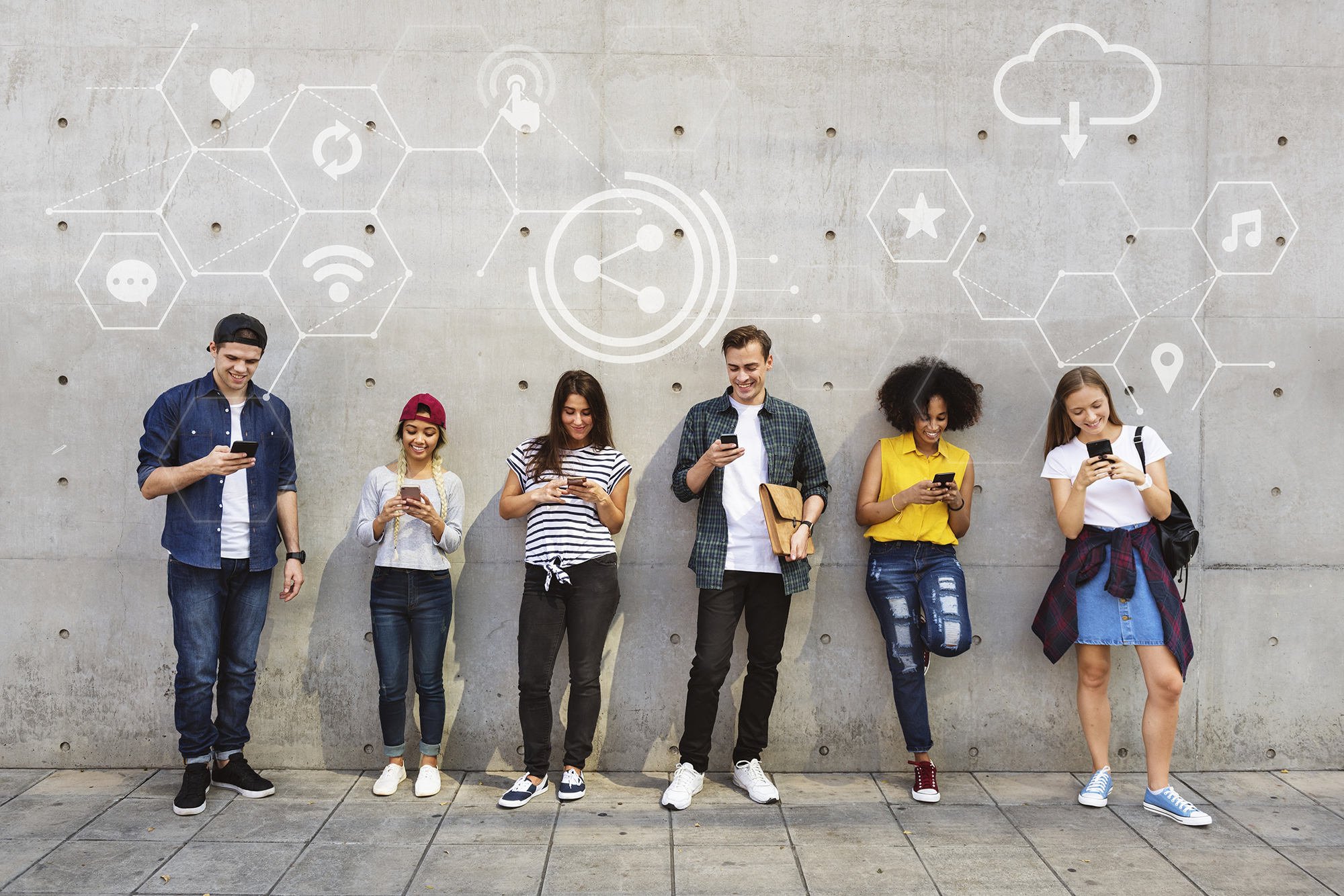 People standing against a wall and using social media on their phone